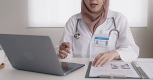 Islam arab GP video call talk share on telemedicine telehealth teleconsult clinic platform app at office desk. Young medic health care worker work for asia people tele consult on online remote visit.