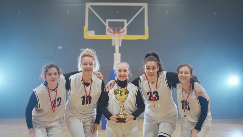 Emotions of victory, team of female basketball players rejoices a victory in international championship, woman holds the gold cup in her hands, 4k slow motion.