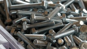 stack of steel fasteners screws,bolts and nuts for sale.hidden metal screws.engineering,industrial shop with screws in cardboard and plastic boxes.4k real time video