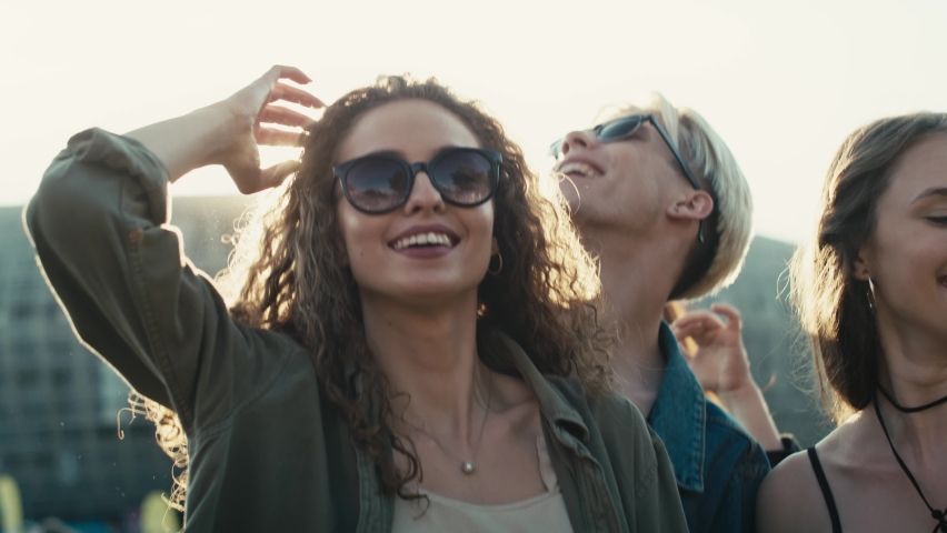 Smiling young caucasian woman with curly hair dancing at music festival among friends. Shot with RED helium camera in 8K.  Royalty-Free Stock Footage #1092588405