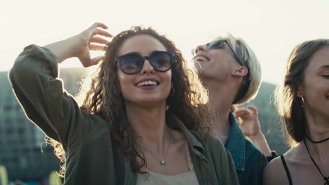 Smiling young caucasian woman with curly hair dancing at music festival among friends. Shot with RED helium camera in 8K.  Adlı Stok Video