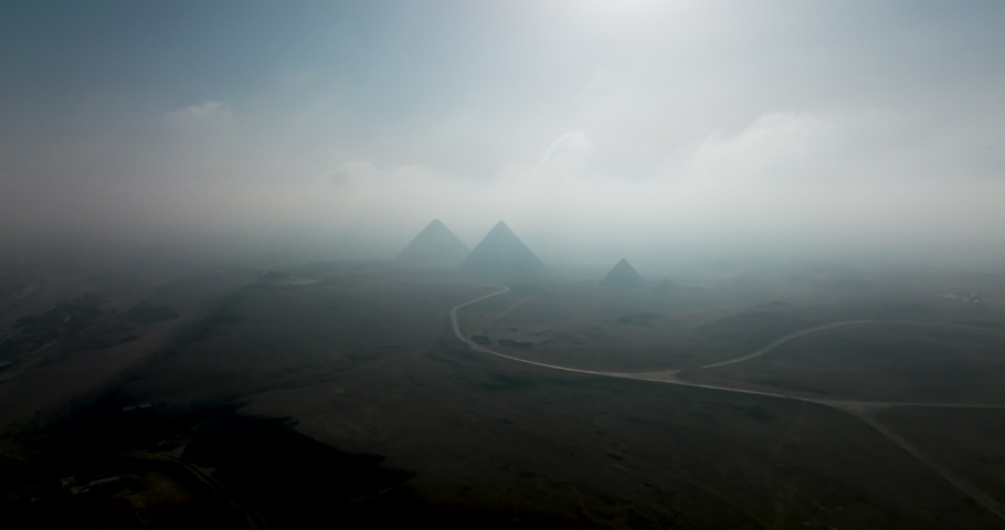 Aerial shot of Egyptian Pyramids in Giza under moving Clouds. Giza Pyramids under clouds, Recorded by Mavic 3 Cine on Apple ProRes 422 HQ 4k DCI Royalty-Free Stock Footage #1092590181
