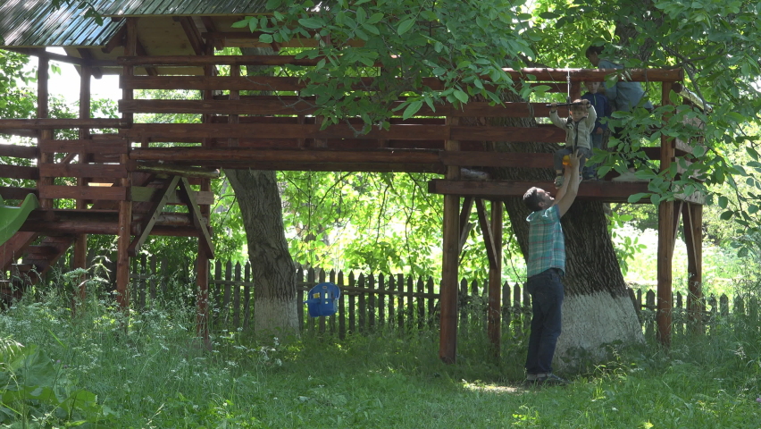 Father holds little son on zip line sliding