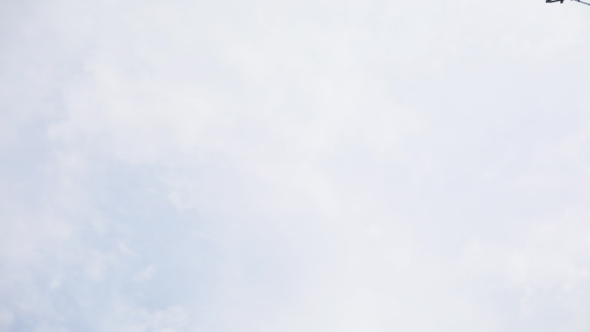 Installation of tower for power transmission lines at construction site against cloudy sky. Technicians work with electrical connection low angle shot