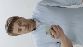 Unhappy man is disturbed by what he sees on smartphone. Surprised man is disturbed by what he sees on his cell phone and shows his green screen smartphone to the camera. Unexpected bill, bad news.