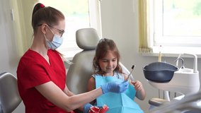 Pediatric dentist teaching oral hygiene lesson for kids in dentistry. 4k video. Dentist shows child how to properly use toothbrush for brush teeth. Jaw anatomical model teeth brushing.