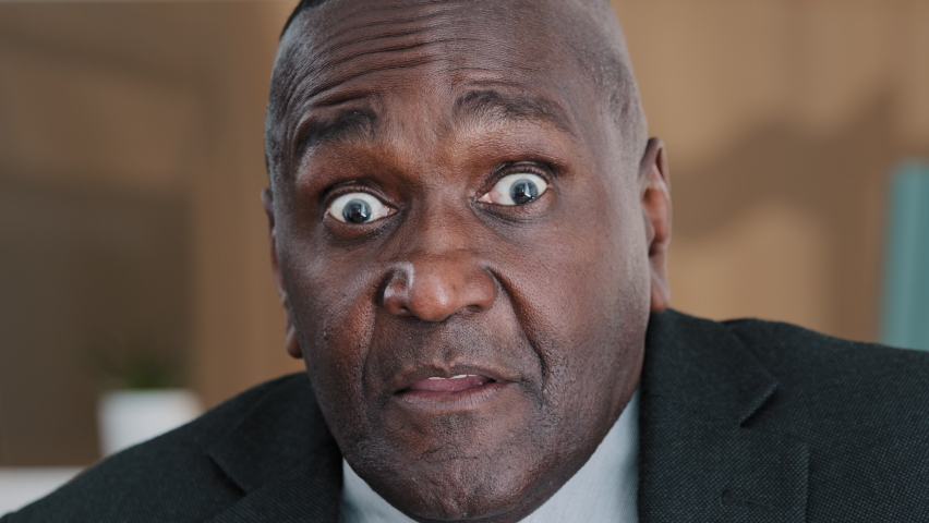 Extreme closeup old wrinkled emotional businessman. African American scared shocked amazed biracial afraid mature 60s man shaking head no uncertain doubt reaction denial reject to question headshot Royalty-Free Stock Footage #1092607311