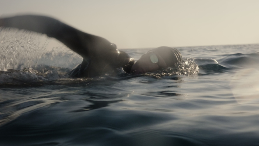 Open water swimming mid tracking shot. Sportsman training forward crawl technique in sea, side view. Professional swimmer workout