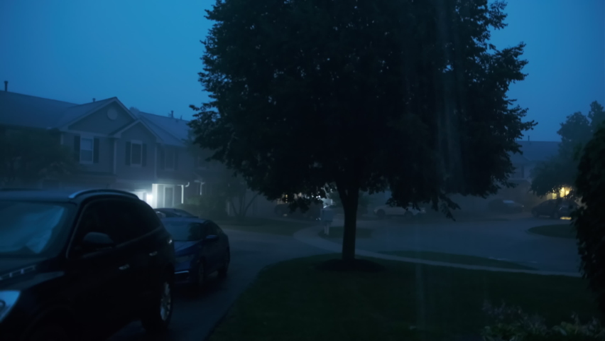 Hard storm, with loud thunder and lightning, a suburban residential street at night time. 