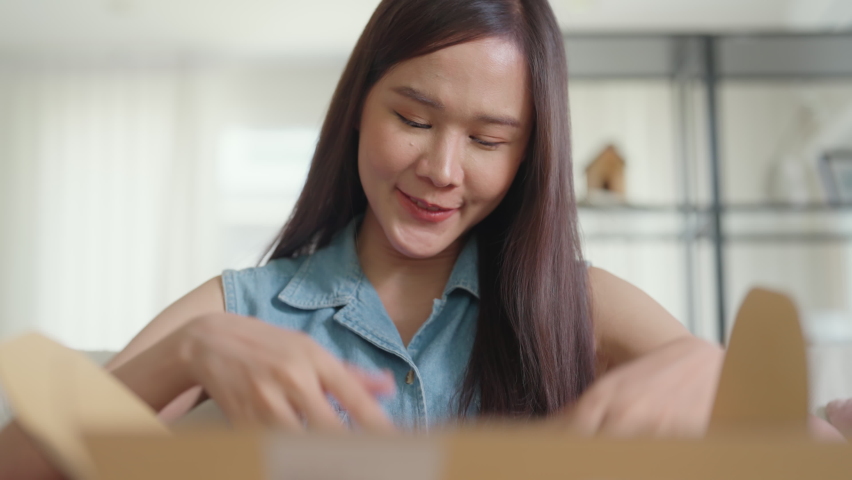 Young Gen Z influencer girl open gift postal mail box sit at home sofa couch. Asia people enjoy wow unbox carton parcel order online buy from small retail store SME shop supply chain omni channel. | Shutterstock HD Video #1092618721
