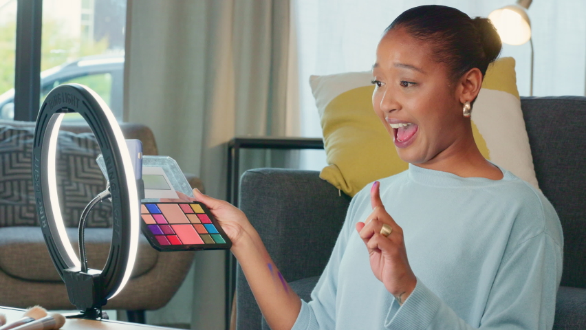Social media influencer testing eyeshadow cosmetics swatch on a live streaming video. Beauty artist showing product online with trendy LED light. Female vlogger recording a makeup tutorial on a phone