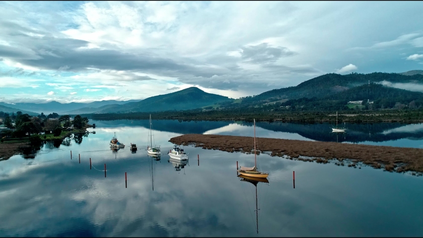 Boats moored on still water in Huon River Tasmania 