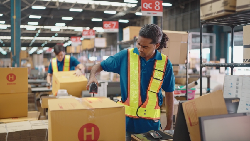 Warehouse worker using a QR code reader, scanning parcels into the system while working inside a large distribution center, worker checking goods packages and making inventory of goods. | Shutterstock HD Video #1092625157