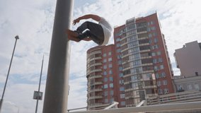 Male parkour athlete performs a trick with overcoming obstacles. Does a back flip from a metal pipe against the backdrop of an urban landscape. Slow motion. - Powered by Shutterstock - Get 15% off with code: PIKWIZARD15