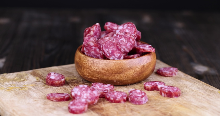 Take with your hands sliced thin sausage with bacon on a wooden dish, sliced pork sausage and other ingredients on the table | Shutterstock HD Video #1092629309