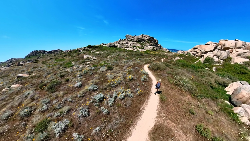 Aerial panorama of Lavezzi island of Lavezzi archipelago in the Strait of Bonifacio. Aerial view of a woman hiking by the island reefs and hills in the Mediterranean sea of Corsica island in France.