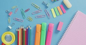 Video of various office supplies, pens, paper clips, pins on blue background. Education, learning and creativity.