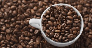 Video of cup of coffee beans over roasted brown coffee beans. Coffee, refreshment and beverages.