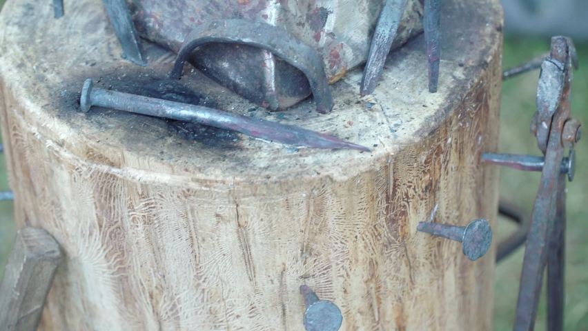 MOSCOW, RUSSIA - June 9, 2022: Portable anvil on a log with blacksmith tools from the time of the Roman Empire. Festival of Historical Reenactment Times and Epochs-2022 in June 2022 in Moscow Russian