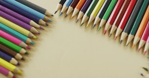 Video of frame with colorful crayons on beige surface with copy space. School equipment, tools, learning and education concept.