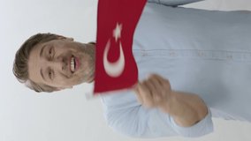 Smiling young man isolated on white background celebrating with Turkey flag. Celebration of special days of countries. Happy young man waving Turkish flag on white background.Vertical Video.
