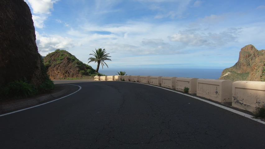 4K POV footage of driving along winding mountain road through beautiful landscape with rocks, cliffs, greenery, highland villages. Typical volcanic island view. Tenerife, Spain. Wide angle video Royalty-Free Stock Footage #1092640621