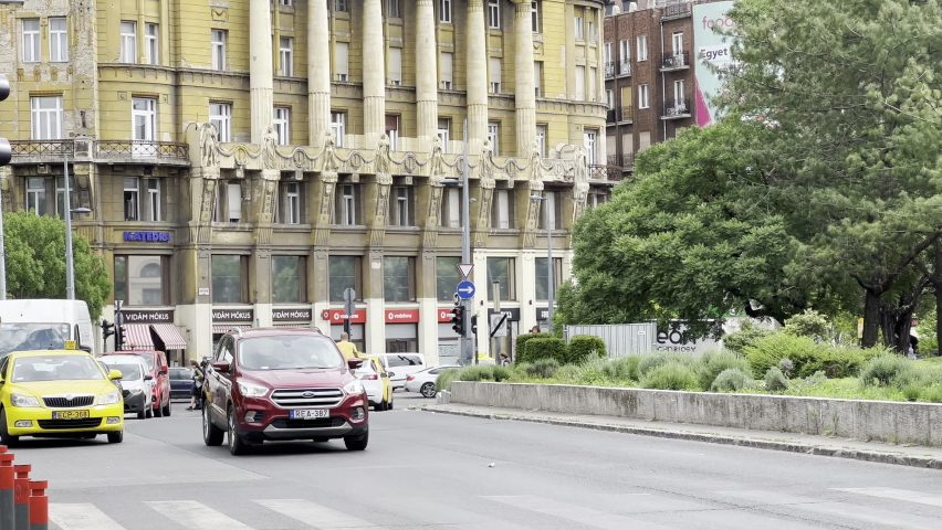 Pedestrians walk along the crosswalk with Anker house in the background. Budapest, Hungary