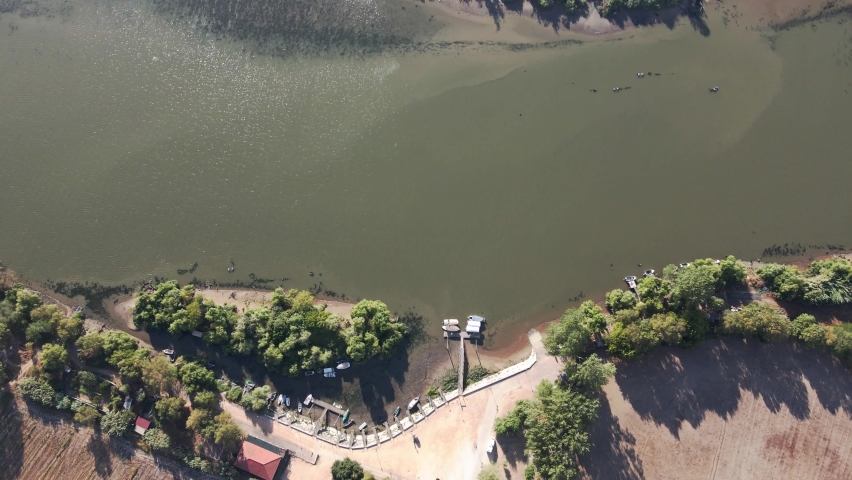 Drone shot top down view going from a boat harbor crossing a river and going to a tropical island with birds flying