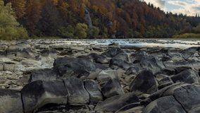 Mountain river wild stone bank with rapids against colorful trees growing on hill slopes under blue sky with floating clouds in autumn 4K video time-lapse