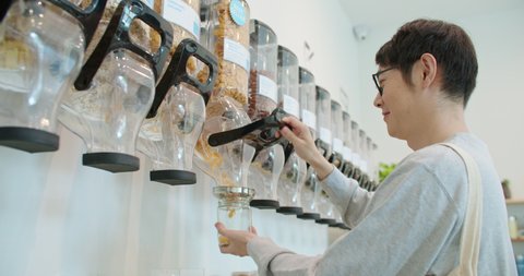 Man pours bio organic product from vending machine to glass jar in zero waste shop. Male buying food in plastic free grocery store. Eco friendly business startup go green market. Reduce Reuse Recycle. 스톡 비디오