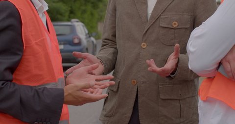 Foreman shaking hands with workers at a construction site, gesticulates during communication. No face. Discussion of plans and work issues. CZ, Kladno, Industrialni, 29.6.22: dziennikarski film stockowy