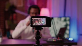 Selective focus on digital video camera screen recording african american content creator streaming live internet show from home. Influencer filming entertainment show for vlog social media post.