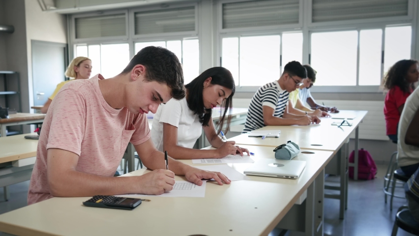Group of high school teenager students taking math exam at classroom - Latin American Girl and Caucasian Boy writing test  Royalty-Free Stock Footage #1092660647