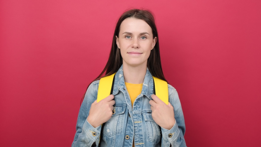 Happy young student woman with yellow backpack looking up, posing isolated over red color background wall in studio with copy space for promotion content. Education in university college concept Royalty-Free Stock Footage #1092662537