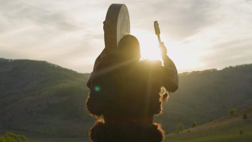 Silhouette of man conducting battle victory ceremony with shaman drum against mountains backside view. Siberian land mystical rituals. Altai culture Royalty-Free Stock Footage #1092662831
