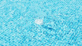 The surface of the pool, the background of the water in the pool. texture of moving transparent water in a blue pool. Water in a swimming pool with light reflections and water movement from filtration