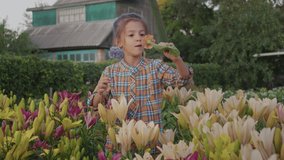 Happy smiling kid girl smells fresh flowers at grandmothers cottage outdoors. Little child learn care and beauty environment, inspiration, imagination development. Funny summertime holidays in village - Powered by Shutterstock - Get 15% off with code: PIKWIZARD15