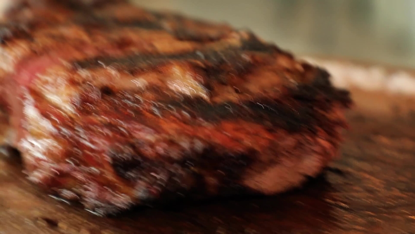 Close up of a juicy Ribeye meat stake, hand cuts a piece with fork and knife. Royalty-Free Stock Footage #1092677229