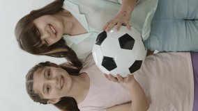 Excited little girls are considering becoming football players when they grow up. Girls are holding a soccer ball. Concept of encouraging young children to do sports.Vertical Video.