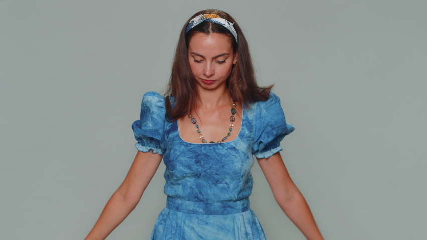 Lovely pretty young woman in blue dress waving, wrapping in Israel national flag, celebrating Independence day. Patriotism. Adult stylish female girl isolated alone on gray studio background indoors