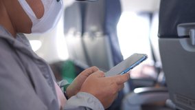 Asian traveler Using Smartphone on flight near window airplane. COVID-19 protection situation in New Normal wear medical face mask protection virus corona pandemic outbreak for traveling - Powered by Shutterstock - Get 15% off with code: PIKWIZARD15