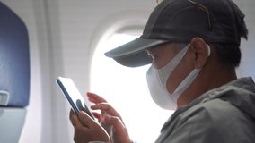 Asian traveler Using Smartphone on flight near window airplane. COVID-19 protection situation in New Normal wear medical face mask protection virus corona pandemic outbreak for traveling - Powered by Shutterstock - Get 15% off with code: PIKWIZARD15