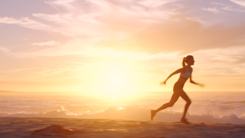 Fit and active jogger running by the ocean and beach shore with sunset sky background and copy space. Beautiful view of a sporty female athlete exercising or doing endurance workout outdoors Royalty-Free Stock Footage #1092691179