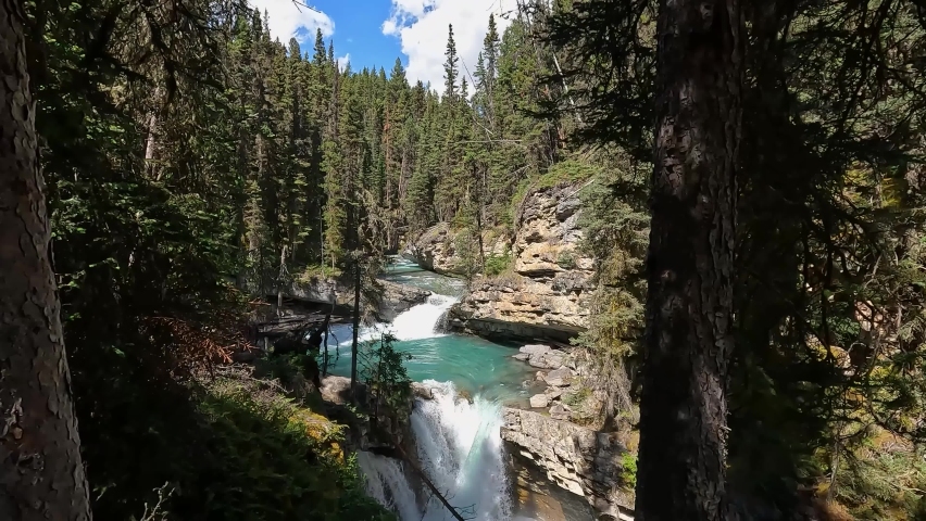 Waterfall in the Canadian Rockies. Johnston Canyon lower falls. Trees, moss and foliage in the background. Banff National Park Alberta Canada. River whistling in the canyon below. White water washout.