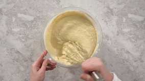 Time lapse. Mixing ingredients in a glass mixing bowl to prepare coconut banana pancakes.