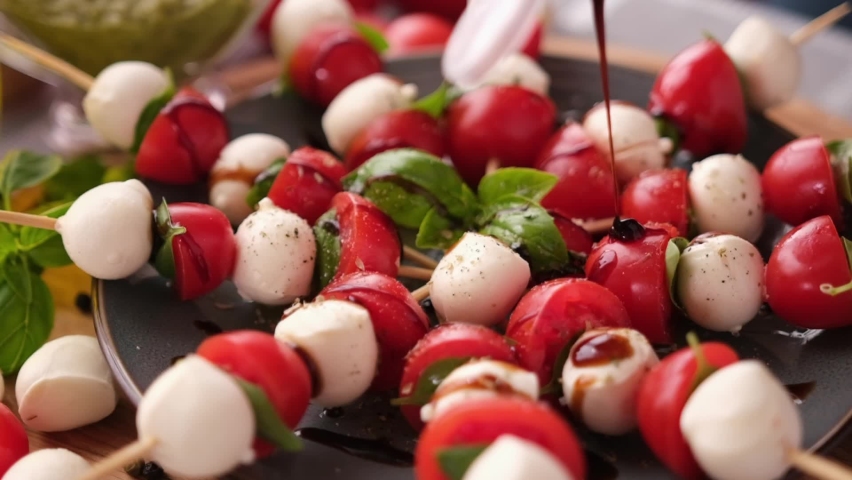 Pouring balsamic sauce on caprese canapes with cherry tomatoes and mozzarella cheese balls | Shutterstock HD Video #1092706273