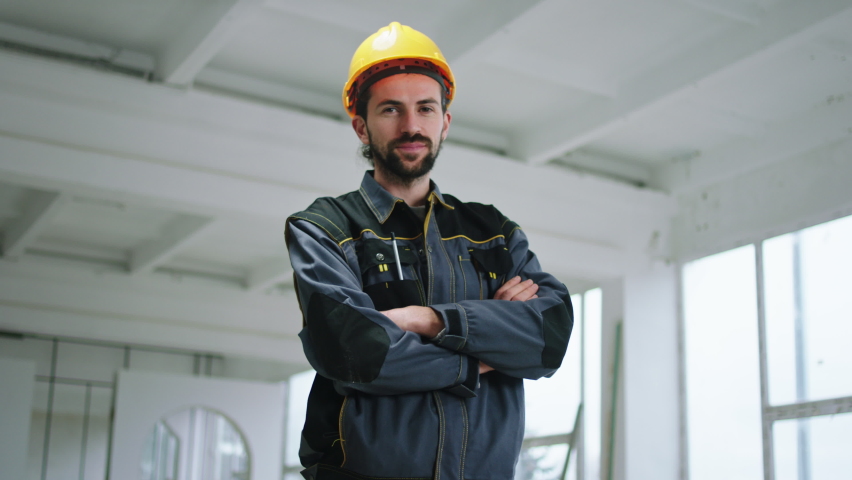 In front of the camera posing charismatic attractive constructor worker man with safety helmet he crossing hands and smiling cute
