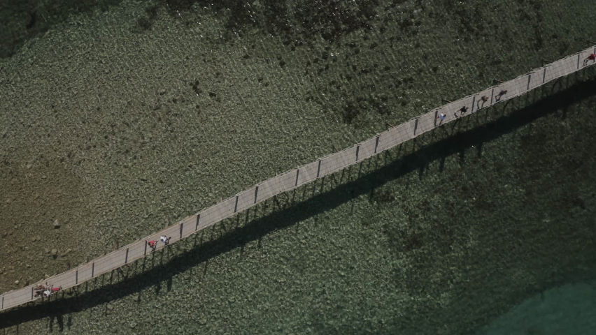 Epic aerial view drone shot of long thin bridge from shore to ocean island.