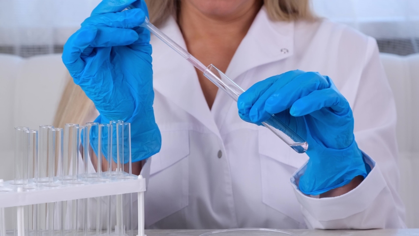Professional scientist takes a sample for a medical experiment. A research chemist works in a laboratory with a micropipette and a microscope | Shutterstock HD Video #1092717133