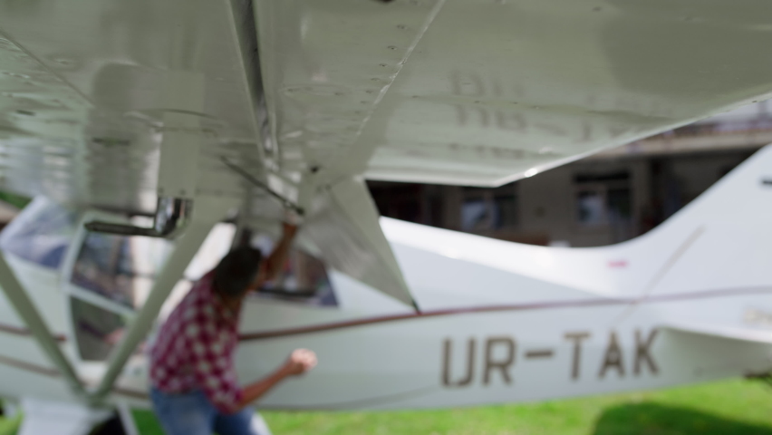 Preflight preparations private airplane by aviation engineer checking wings. Professional aircraft specialist inspecting small plane after landing on rural runway sunny day. Aviator work concept.